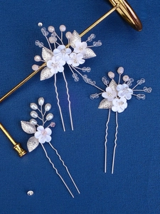 Detail of three-piece bridal hair pins with white ceramic flowers and crystal beads