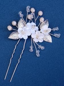 Macro detail of bridal hair comb with handmade ceramic flowers and silver leaves