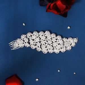 Elegant silver bridal hair comb with shimmering rhinestones and pearls on blue background