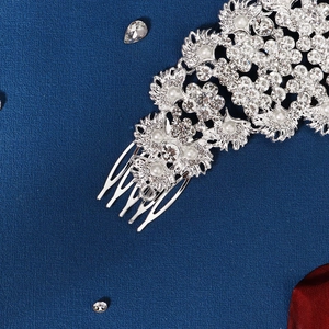 Silver bridal hair comb with white rhinestones and pearls on a blue background