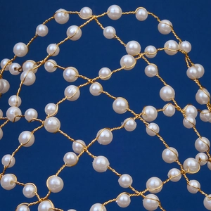 Vue macro d'un serre-tête de mariée aux perles blanches tissées en fil doré poli