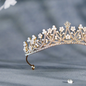 Detailed close-up of golden bridal crown with white pearls and sparkling rhinestones