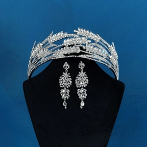 Detailed view of luxury bridal crown and tassel earrings set on black velvet stand