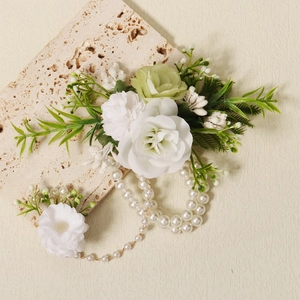 Elegant floral pearl bracelet with white roses and green leaves on stone display