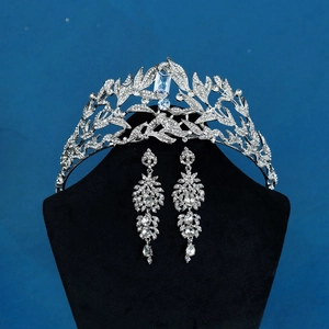 Close-up of bridal jewelry set with silver leaf crown and long rhinestone earrings