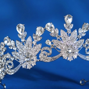 Elegant silver bridal crown with floral rhinestone patterns on deep blue background