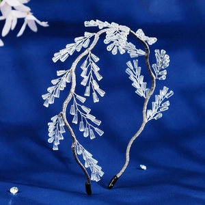 Elegant silver bridal headband with crystal beads and floral branch design on blue background