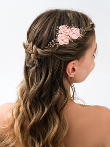 Close-up of bridal hair comb with pink fabric roses and gold leaves on wavy hair