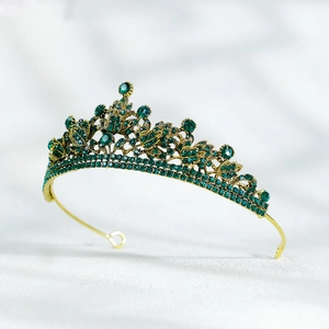 Détail d'un diadème de mariée doré serti de strass vert émeraude avec un design floral