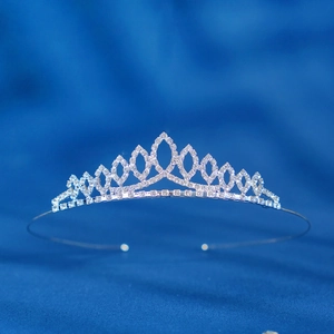 Detailed close-up of a silver tiara headband with sparkling rhinestones on blue fabric