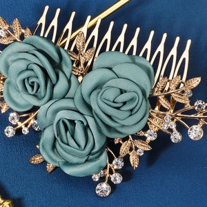 Detail view of teal fabric roses with gold alloy leaves and crystal rhinestones on hair comb