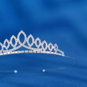 Close-up of elegant silver tiara with marquise-cut rhinestones on royal blue satin