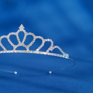 Close-up of sparkling silver crystal tiara with intricate zircons on deep blue satin