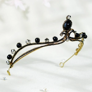 Detail of vintage bronze bridal crown with black and silver rhinestones on white surface