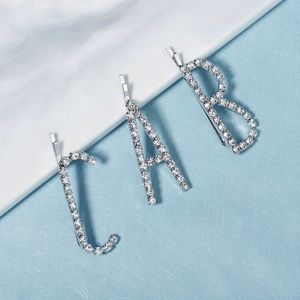 Détail de barrettes à lettres A B C argentées étincelantes avec strass sur marbre