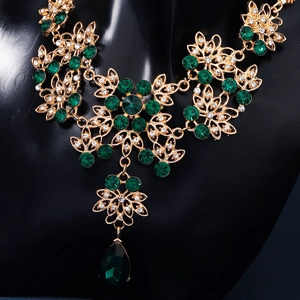 Detail showing vintage emerald green rhinestone necklace with golden filigree patterns