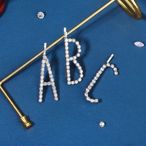Lot de barrettes argentées avec strass lettres A B C sur un fond texturé bleu foncé