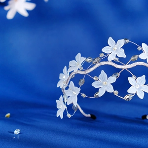 Close-up of white matte flowers and diamond beads on a crystal floral headband