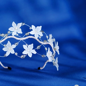 Close-up of mesh floral headband with white matte flowers and crystal beads detail