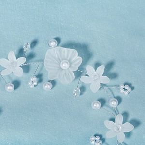 Détail d'un serre-tête floral fait main avec pétales de résine mate, perles et fil d'argent