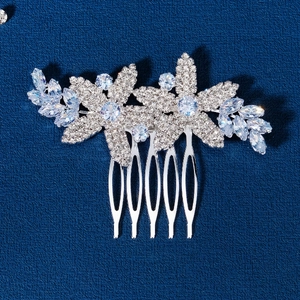 Silver bridal hair comb with zircon floral motifs and rhinestones on blue background