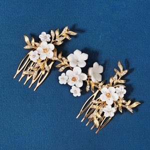 Détail de trois peignes à cheveux de mariée avec fleurs en céramique blanche et feuilles d'or