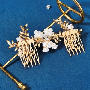 Détail de peignes à cheveux vintage dorés avec fleurs en céramique et feuilles