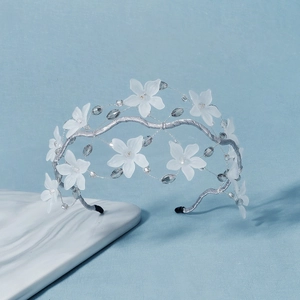 Floral crystal beaded headband with white petals and silver wire on light blue background