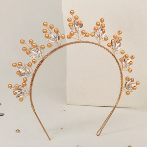 Détail d'un serre-tête doré avec perles orange et cristaux marquise élégants