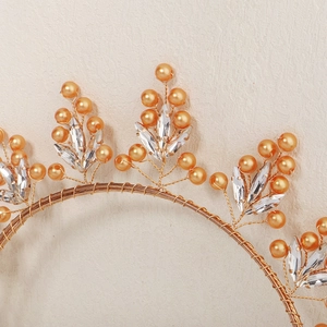 Détail d'un serre-tête fait main en fil doré avec perles orange et feuilles en cristal