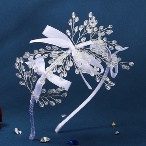 Détail de perles en cristal et nœuds en satin blanc sur un serre-tête en fil d'argent