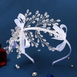 Gros plan sur un serre-tête de mariée fait main avec nœud blanc et perles de cristal