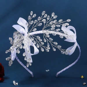 Détail du serre-tête en cristal blanc avec de grands nœuds en satin pour coiffure de mariée