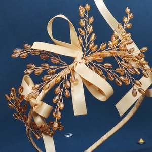 Gros plan d'un serre-tête artisanal avec perles dorées champagne et un nœud en satin