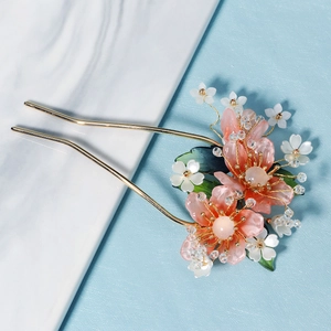 Détail d'une épingle à cheveux fleur de pêcher en résine avec perles et métal doré élégant