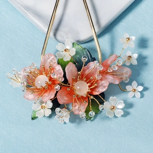 Détail d'épingle à cheveux fleur de pêcher en résine rose avec fil doré et feuilles