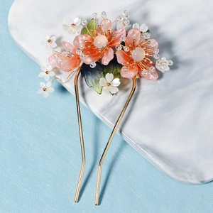 Détail d'épingle à cheveux fleur de pêcher en résine rose avec fourche dorée