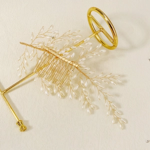 Close-up of handmade bridal hair comb with gold wire branches and white pearl beads