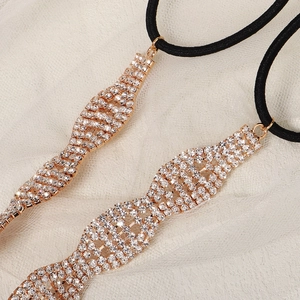 Dettaglio di fasce per capelli ondulate dorate con strass su pizzo bianco