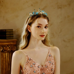 Exquisite gold bridal crown with blue crystals and white pearls worn by a model