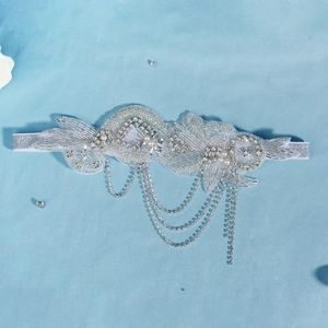 Détail d'un bandeau de mariée avec paillettes argentées, perles et glands en strass