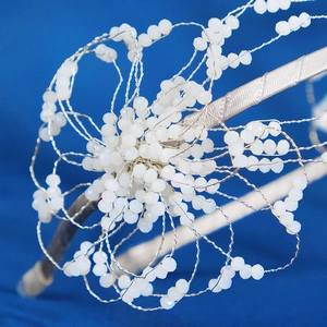 Macro shot of handcrafted white beaded floral bridal headband with silver wire detail