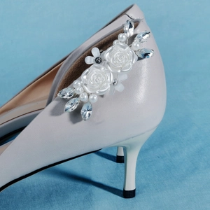 Detail of detachable bridal shoe clips with white flowers and pearls on high heels