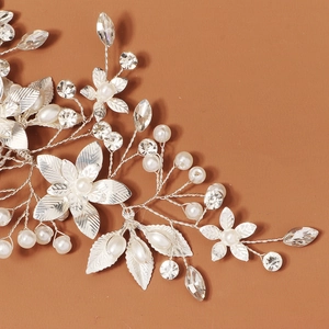 Close-up of bridal hair comb with silver metal leaves, white pearls and clear rhinestones