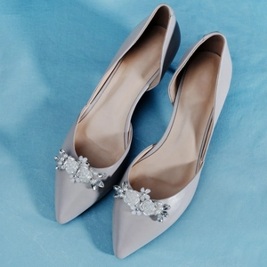 Close-up of detachable pearl flower clips with rhinestones on grey high heel shoes