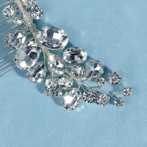 Macro shot of silver bridal hair comb with hand-wired rhinestones on a blue surface