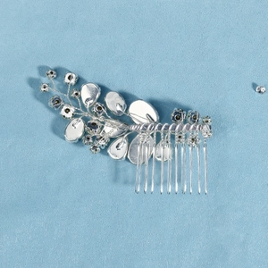 Macro shot of silver bridal hair comb with handmade rhinestones and leaf motifs