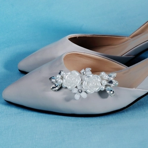 Detailed view of removable bridal shoe clips with white flowers and elegant pearls