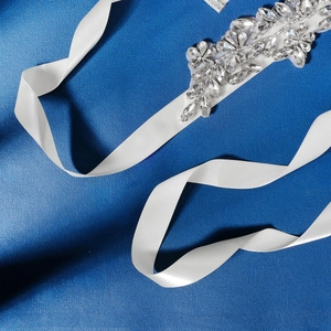 Detail of bridal waist belt featuring sparkling rhinestones on a white satin ribbon