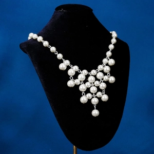 Détail d'un collier de perles vintage avec un pendentif géométrique entrelacé